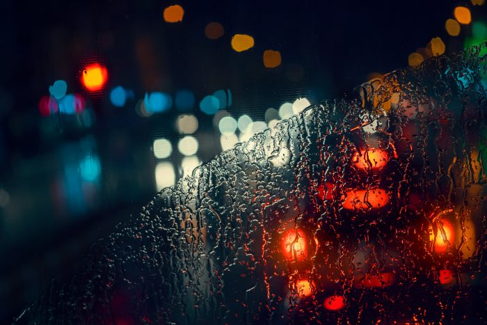 blurry cars and lights in traffic in a rainy night seen through windscreen